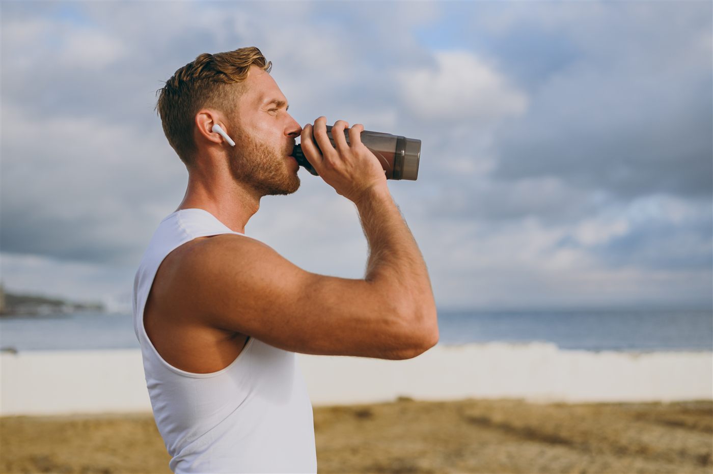 Man drinking a protein shake on the beach